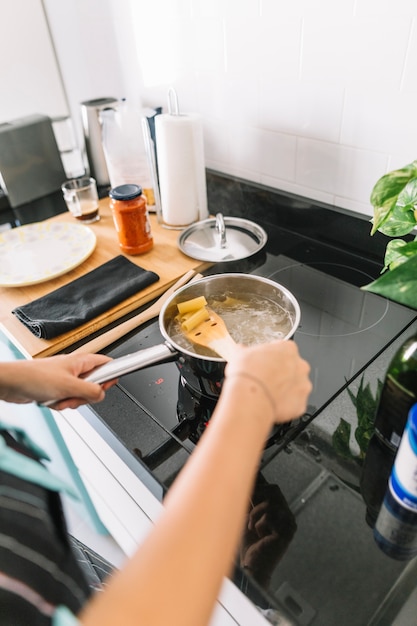 Free Photo woman preparing rigatoni pasta in saucepan