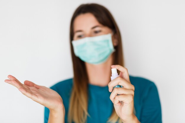 Woman in protective mask washing hands with hand sanitizer