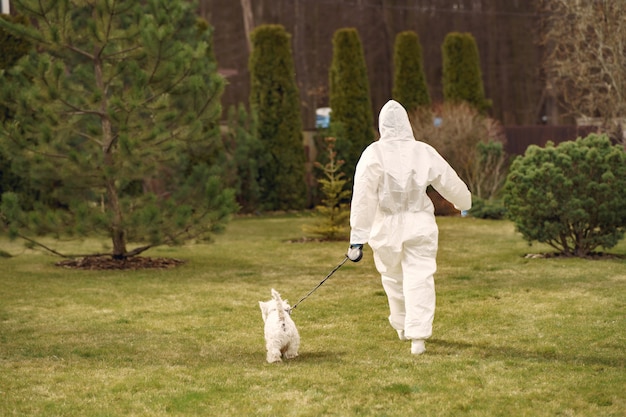 Free photo woman in a protective suit walking with a dog