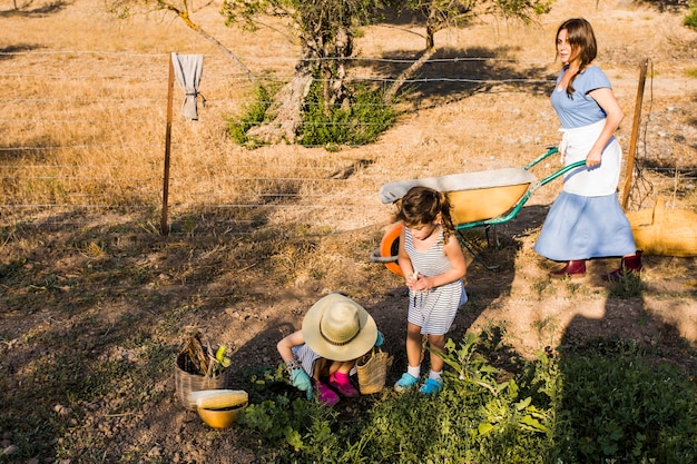 Free Photo woman pushing wheelbarrow with her daughter harvesting in the field