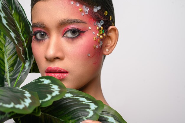 Woman put on pink makeup and decorated with leaves isolated on white