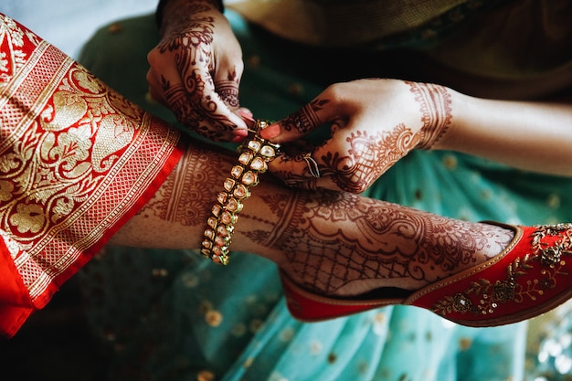 Free photo woman puts bracelet on hindu bride's leg