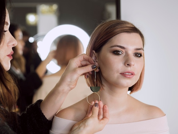 Woman putting earrings on model