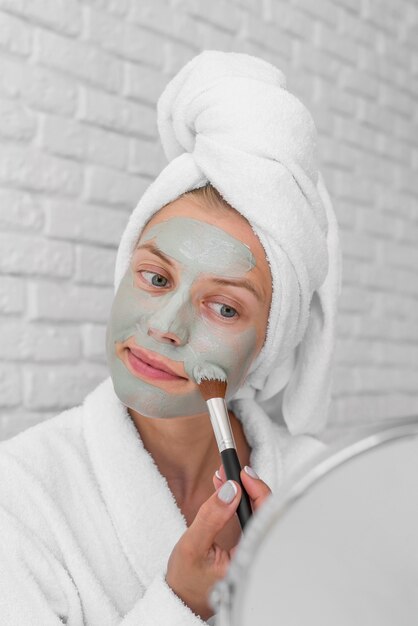 Woman putting on facial treatment close-up