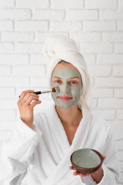 Woman putting on facial treatment front view