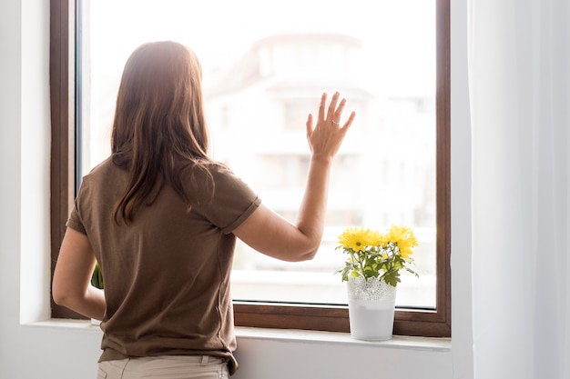 Woman in quarantine at home looking through the window