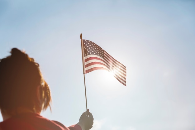 Free Photo woman raising american flag to bright sun