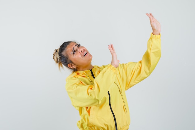 Free Photo woman raising hands to defend herself in sport suit and looking scared , front view.