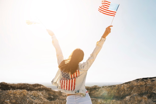 Free photo woman raising hands with flags on mountain