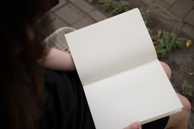 Free photo woman reading blank book in garden