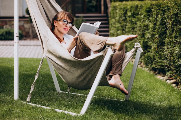 Free photo woman reading a book in the garden by the house