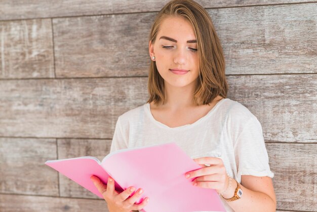 Woman reading book leaning over the wooden wall