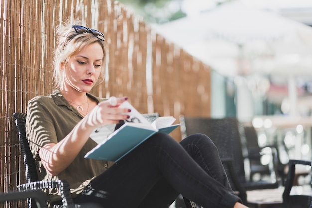 Free Photo woman reading book near fence