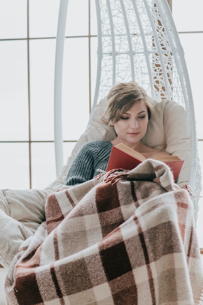 Free photo woman reading on hanging chair