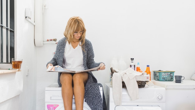 Free photo woman reading magazine in laundry