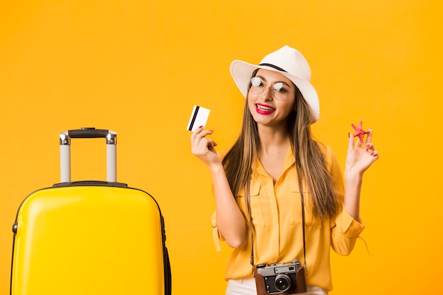 Woman ready for trip posing with credit card and luggage