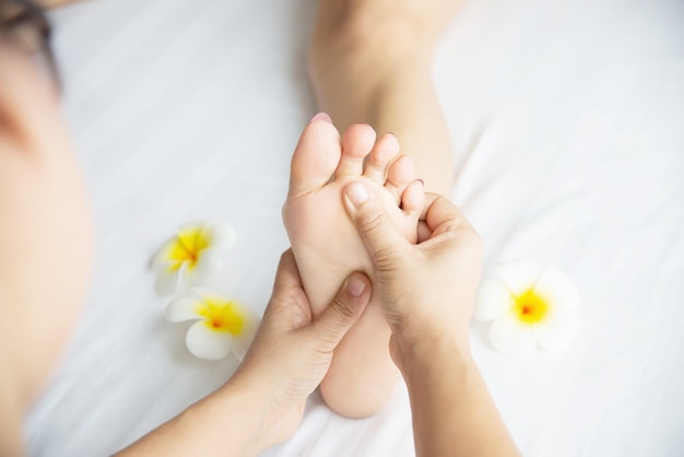 Woman receiving foot massage service from masseuse close up at hand and foot - relax in foot massage therapy service concept