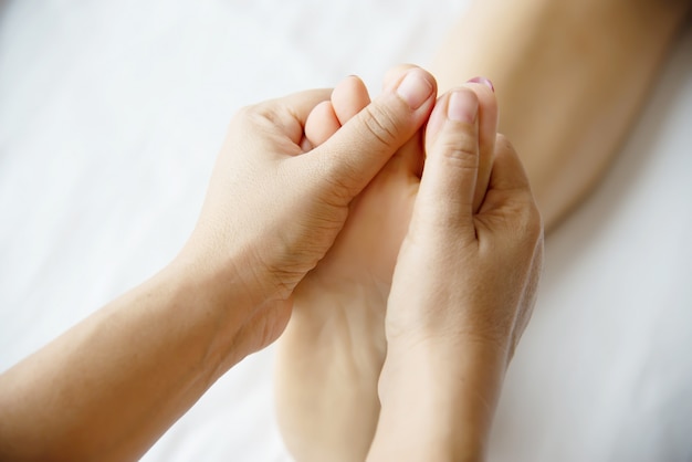 Woman receiving foot massage service from masseuse close up at hand and foot - relax in foot massage therapy service concept