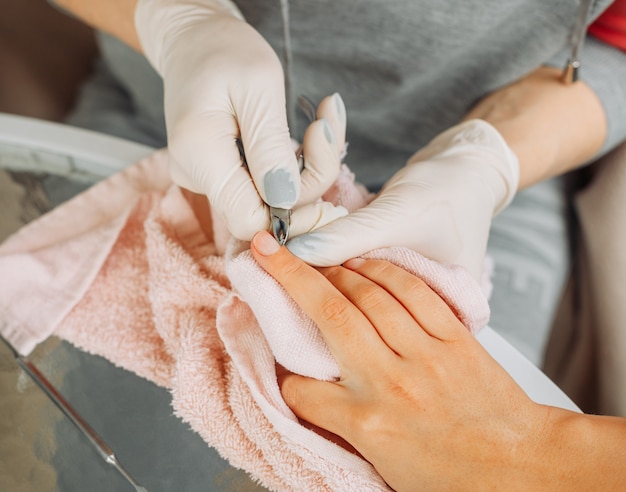 Free photo a woman receiving manicure from a woman in gloves and mask in beauty salon during daytime