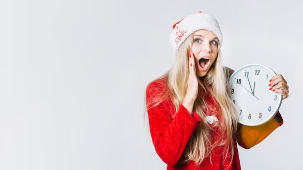 Woman in red clothes holding clock in hands 