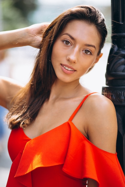 Woman in red dress model posing outside