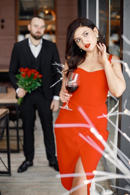 Woman in red elegant dress standing in restaurant waiting for her boyfriend