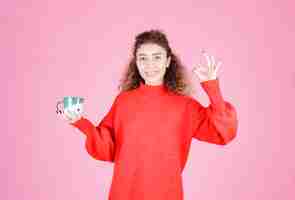 Free photo woman in red shirt holding a coffee mug and enjoying the taste.