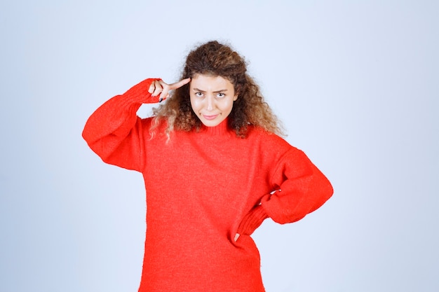 Free photo woman in red shirt pointing her head and thinking.