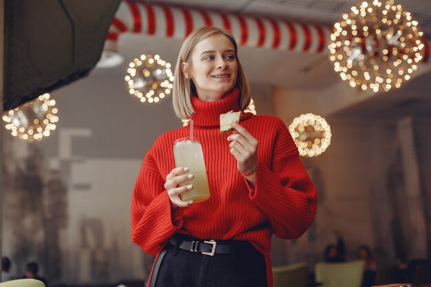 Free photo woman in a red sweater. lady drinks a cocktail.