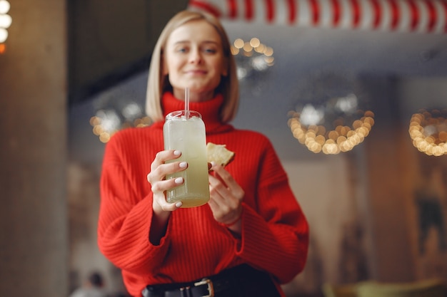 Free photo woman in a red sweater. lady drinks a cocktail.