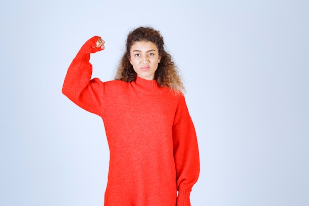 woman in red sweatshirt showing her fist and meaning her power.