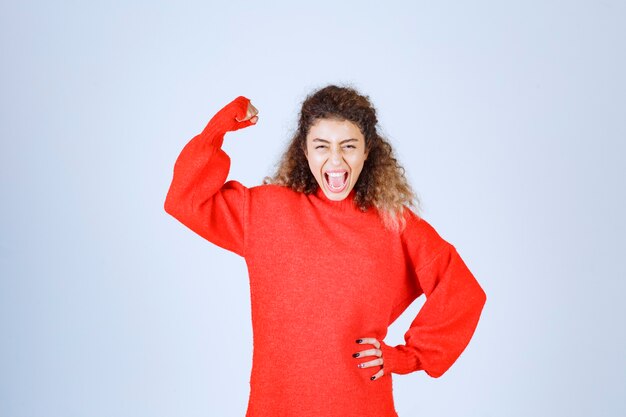 woman in red sweatshirt showing her fist and meaning her power. 