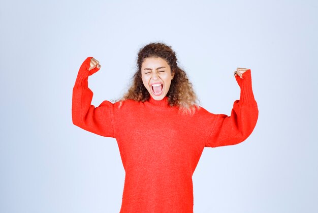 woman in red sweatshirt showing her fist and meaning her power. 