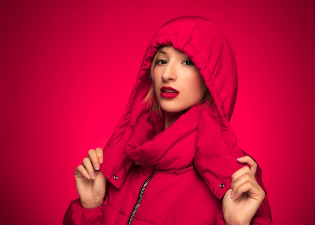 Free photo woman in red winter hooded jacket purple background