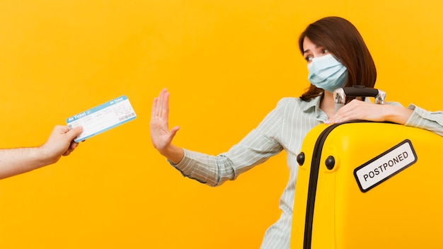 Free photo woman rejecting a plane ticket while wearing e medical mask