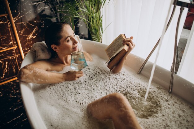 Woman relaxing in bath with bubbles and drinking wine