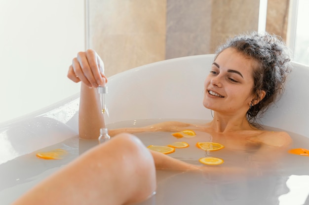 Free Photo woman relaxing in bathtub with orange slices