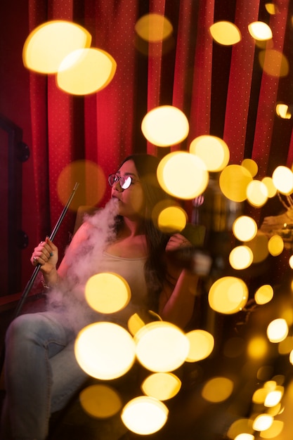 Free Photo woman relaxing by vaping from a hookah in a bar