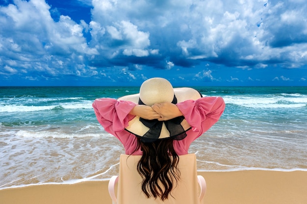 Free photo woman relaxing on deck chair at beach and looking at ocean.