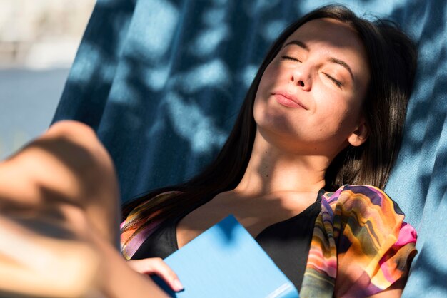 Woman relaxing in hammock while at the beach with book