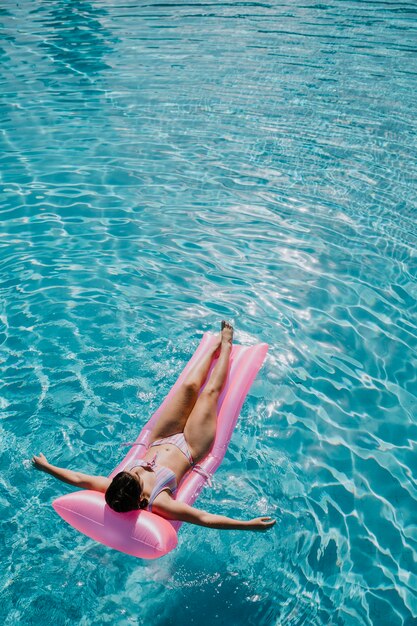 Woman relaxing on mattress in pool