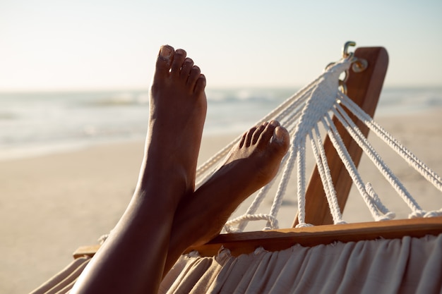 Free photo woman relaxing with feet up in a hammock on the beach