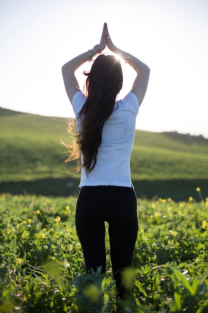 Woman relaxing with hands up on green field