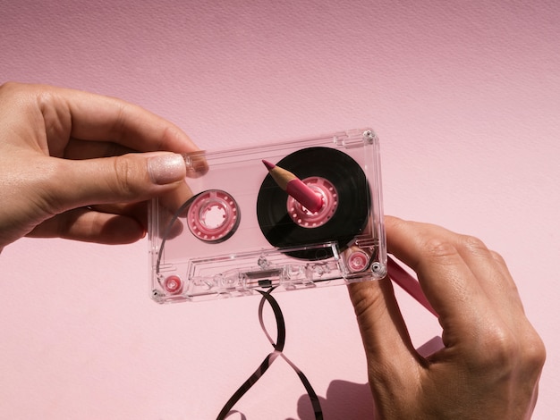 Free Photo woman repairing broken cassette tape with pink pencil