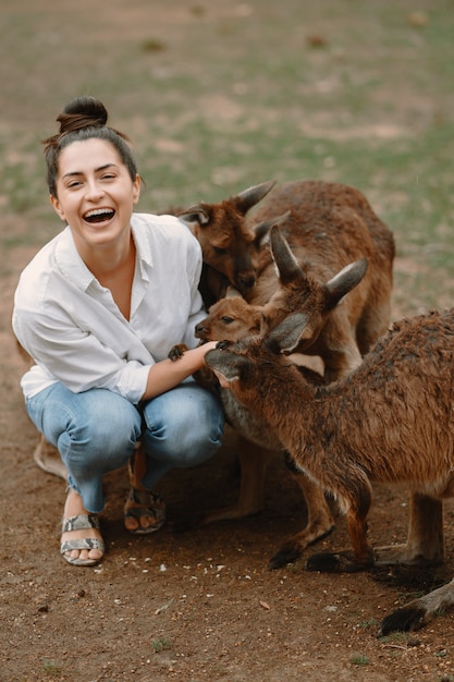 Woman in the reserve is playing with a kangaroo