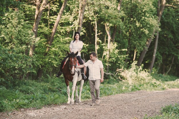 Woman riding a horse and her husband walk