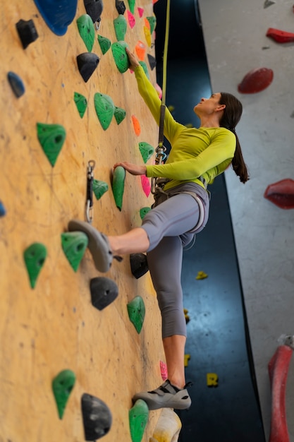 Free photo woman rock climbing indoors in the arena