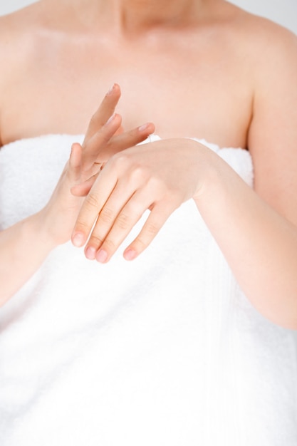 Free photo woman rubbing cream on hands, wear towel