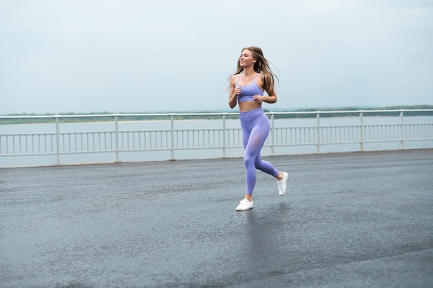 Woman running along the lake long shot