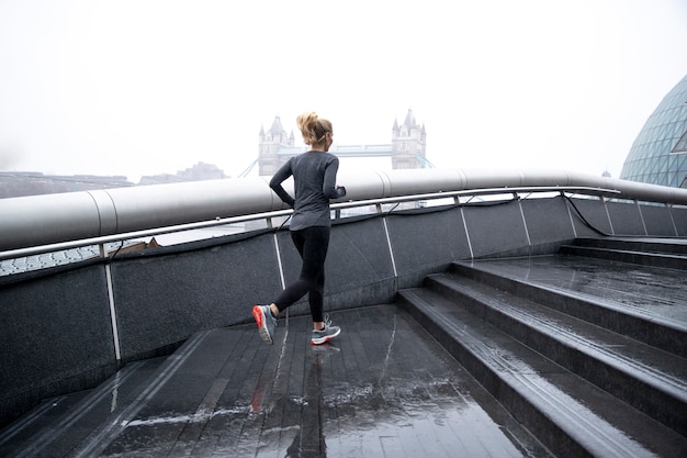 Woman running in the city streets while it rains